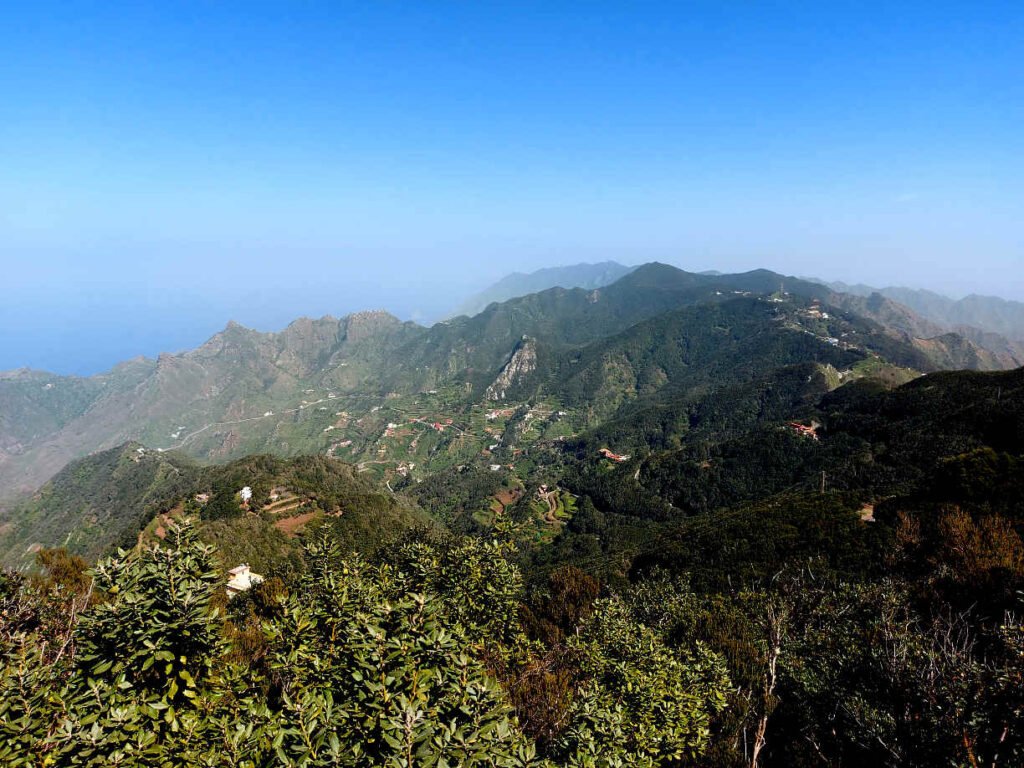 Vista panorámica del macizo de Anaga desde la zona de Los Catalanes, con montañas verdes, caseríos dispersos y el océano al fondo en Tenerife